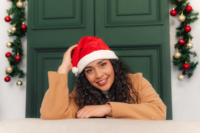 A festive portrait of a young woman in a Santa hat and cozy sweater, exuding holiday cheer.