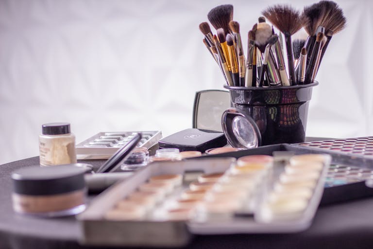 Close-up of a professional makeup brush set and cosmetics on a table for beauty use.