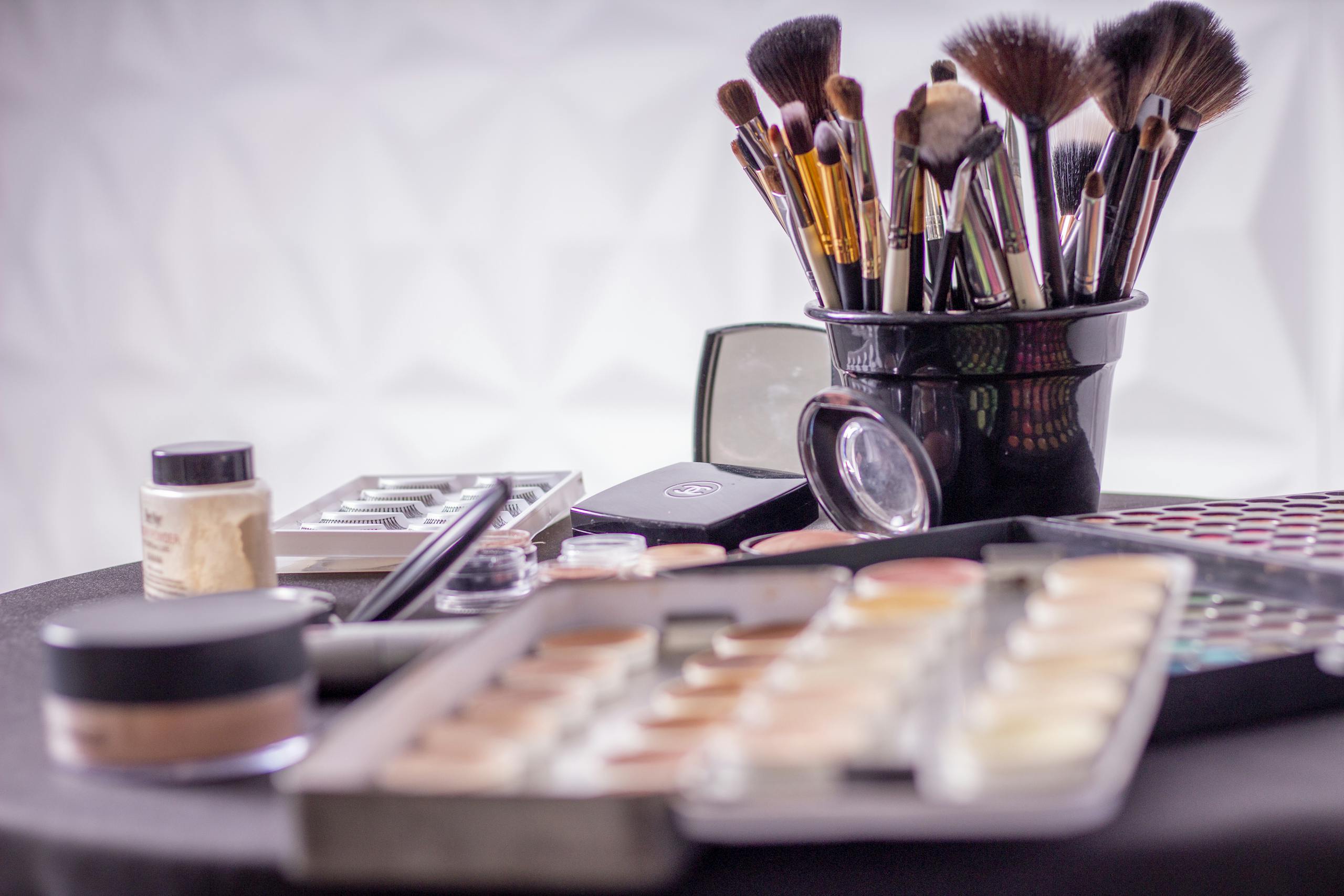 Close-up of a professional makeup brush set and cosmetics on a table for beauty use.
